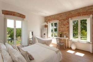 a bedroom with a white bed and a brick wall at Langhe Country House in Neive