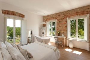 ein Schlafzimmer mit einem weißen Bett und einer Ziegelwand in der Unterkunft Langhe Country House in Neive