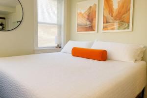 a white bed with an orange pillow on top of it at King Bed Sleeps 3 2 Beds Walkable Cozy in Philadelphia