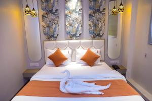 a bedroom with a white bed with a swan on it at Ashray Guest House in Kalyan