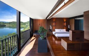 a bedroom with a bed and a balcony with a view at The Lalu Sun Moon Lake in Yuchi