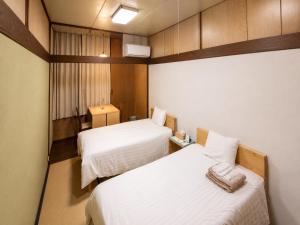 a hotel room with two beds with white sheets at Hotel shirahama in Shirahama