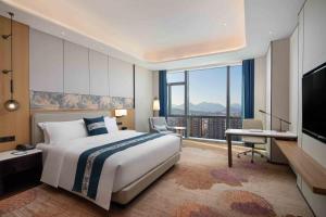 a bedroom with a bed and a desk and a television at Wyndham Shanwei Haifeng in Shanwei