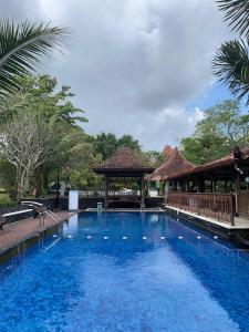 ein großer blauer Swimmingpool mit einem Pavillon in der Unterkunft Java Village Resort Yogyakarta in Yogyakarta