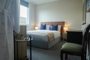a bedroom with a bed with blue pillows and a chair at Oxford on Otho in Inverell