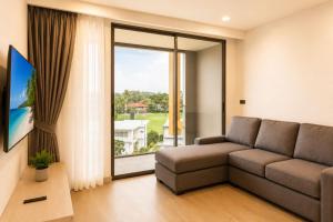 a living room with a couch and a large window at Modern 2BR Apartment with Golf View in Laguna Phuket - Condo Ozone 108-156 in Laguna Phuket