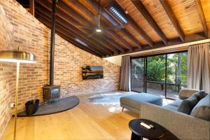 a living room with a couch and a brick wall at Kookaburra Retreat in Berkeley Vale
