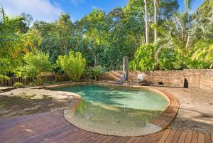 a swimming pool in a yard with a brick wall at Kookaburra Retreat in Berkeley Vale