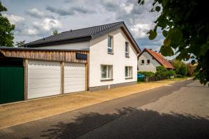 a white house with a garage on a street at FeHaus am Walnussbaum in Starsow