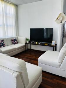 a living room with white furniture and a flat screen tv at Corazón garden in Piura