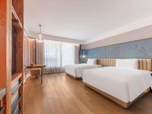 a hotel room with two beds and a desk at Mercure Beijing Dongzhimen in Beijing