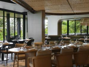 Mövenpick Kigali في كيغالي: غرفة طعام بها طاولات وكراسي ونوافذ