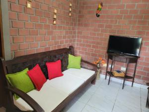 a couch with colorful pillows in a room with a brick wall at Flat Alto Padrão in Gravatá