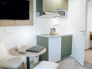 a small kitchen with a table and a sink at Adagio Access Bordeaux Sud Pessac in Pessac