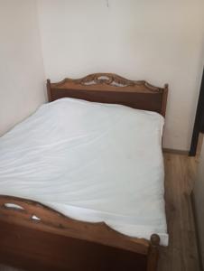 a bed with a wooden headboard and a white pillow at Apartment in the center of Sevan city, in Sevan