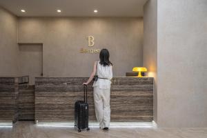 a woman is pulling a suitcase in an airport at Bergen Hotel Daejeon Yuseong in Daejeon