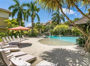 a resort with a pool and lounge chairs and palm trees at Luxury 2 Bedroom apartment, Treetop views, Resort with 4 swimming pools in Cairns North
