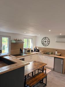 a kitchen with a table and a clock on the wall at Gite Climatisé Les Terrasses Perchées 2 Chambres in Saint-Vincent