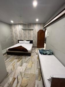 a bedroom with two beds and a stone floor at Hotel Maa Parwati in Ujjain