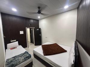 a room with two beds and a ceiling fan at Hotel Maa Parwati in Ujjain
