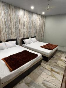 a bedroom with two beds and a wall at Hotel Maa Parwati in Ujjain