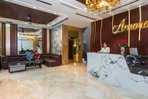 a woman standing at a counter in a lobby at Amora Hotel in Nha Trang