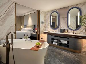 a hotel bathroom with a tub and a bed at Fairmont Hanoi in Hanoi