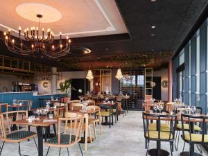a restaurant with wooden tables and chairs and a chandelier at Mercure Quimper Kerlic in Quimper