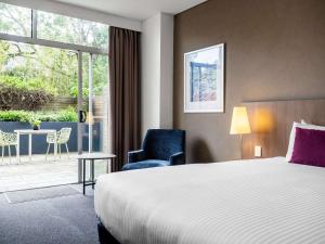a hotel room with a bed and a chair and a window at Mercure Sydney St Leonards in Sydney