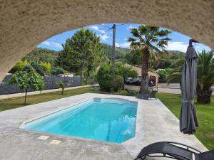 a swimming pool in a yard with an umbrella at La Bastide Bleue in Anduze
