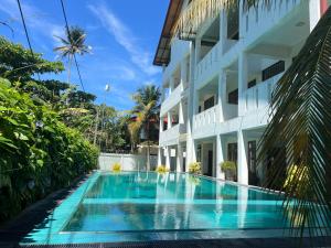 a swimming pool in front of a building at Athithi Villa in Hikkaduwa