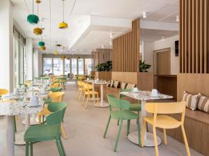 a dining room with tables and chairs and windows at Adagio Access Paris Nanterre in Nanterre
