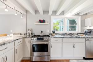a kitchen with white cabinets and a stainless steel stove at Crosswinds Near Beach & Shops in Kennebunk