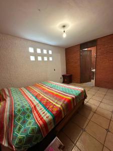 a bedroom with a bed with a colorful blanket on it at Quinta Huicochea in Cuernavaca +39 photos