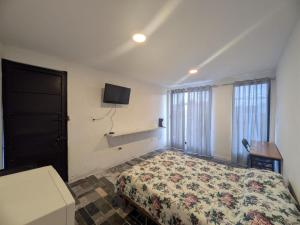 a bedroom with a bed and a tv on the wall at Nova Suites in San Juan Xilotzingo
