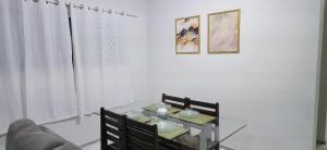 a dining room with a glass table and a couch at Casa Cabugi Ponta Negra JR in Natal