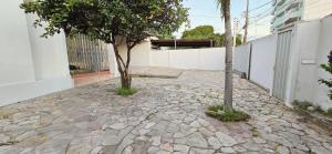 a stone walkway with a tree and a building at Casa Cabugi Ponta Negra JR in Natal