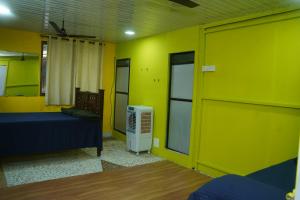 a room with a bed and a yellow wall at Dr Vijeta's Wellness Retreat in Alībāg