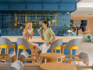 a man and a woman sitting in chairs with drinks at ibis Styles Phuket Bangtao in Bang Tao Beach