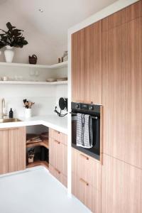 a kitchen with wooden cabinets and a microwave at The Antidote Luxe Off-Grid Tiny Home Escape on Private Farm Stay in Farmeadow