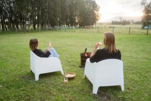 two women sitting in chairs in a field drinking wine at The Antidote Luxe Off-Grid Tiny Home Escape on Private Farm Stay in Farmeadow