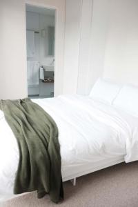 a white bed with a green blanket on it at The Antidote Luxe Off-Grid Tiny Home Escape on Private Farm Stay in Farmeadow