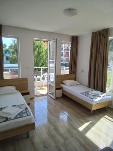 a bedroom with two beds and a balcony at Family Hotel PUDEV in Sunny Beach