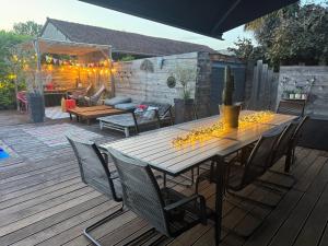 a wooden table with chairs on a wooden deck at La Villa d'ElodibiZa, 45mn de Paris en train avec piscine ! in Écuelles