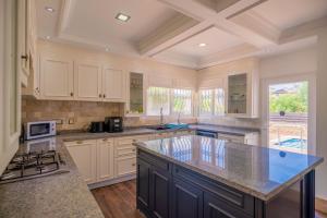 a large kitchen with white cabinets and a large island at Poolside Bar Villa Sea Views atalky in Klepini