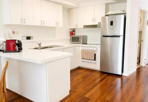 a kitchen with white cabinets and a stainless steel refrigerator at Esplanade Views Heart of Freo Family Stay in Fremantle +19 photos