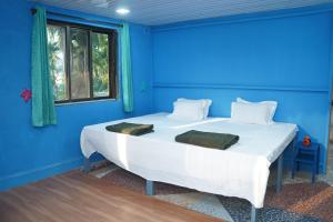 a blue bedroom with a white bed with a blue wall at Dr Vijeta's Wellness Retreat in Alībāg