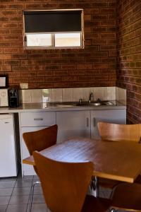 a kitchen with a wooden table and a sink at Bridge Motor Inn Tocumwal in Tocumwal