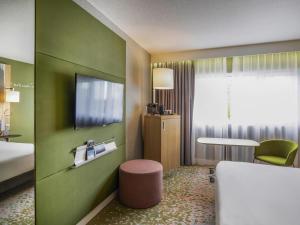 a hotel room with a bed and a tv on a wall at Mercure Reims Parc Des Expositions in Reims
