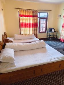 two beds sitting in a room with a window at Dhulikhel Training center in Dhulikhel